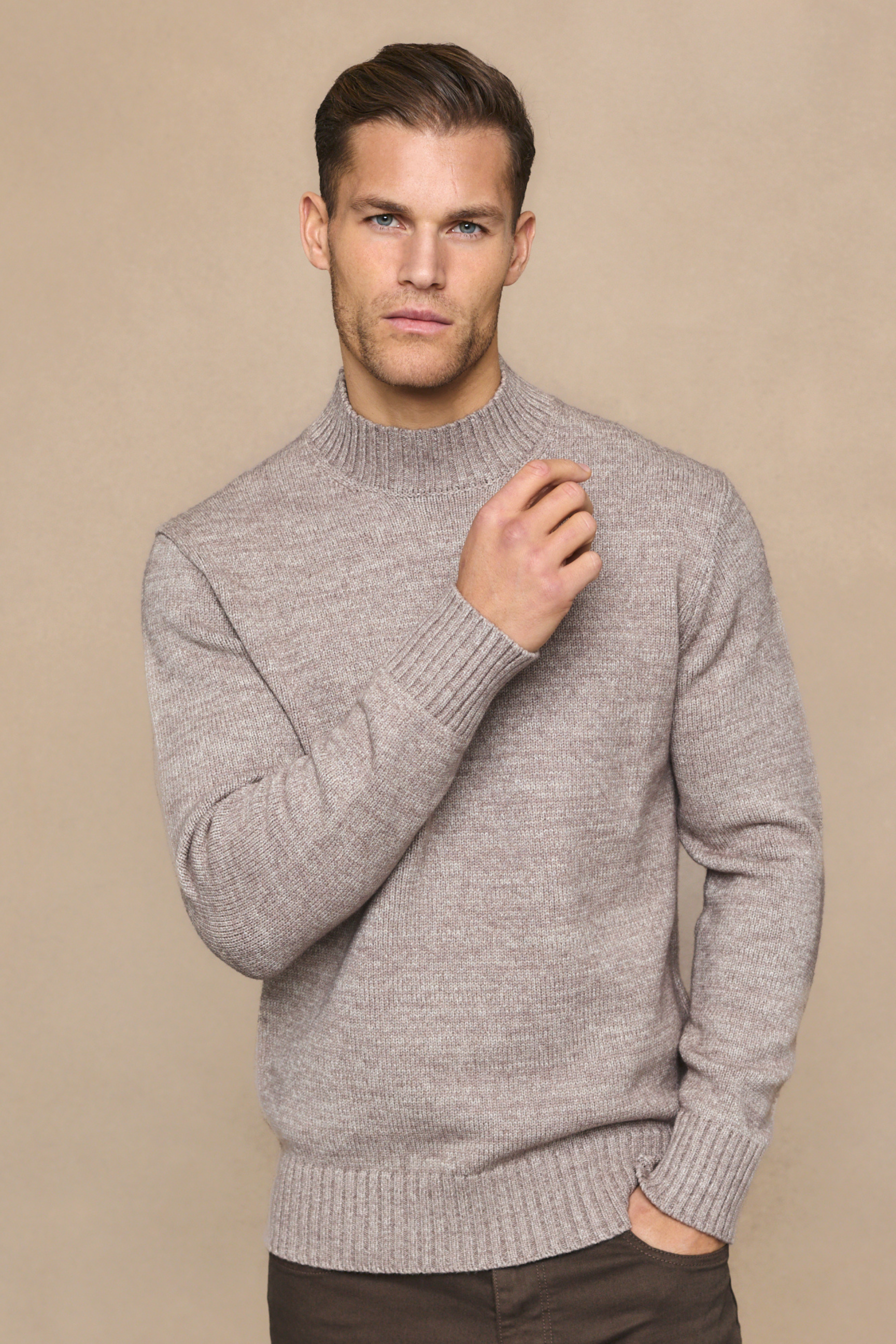 Man wearing a light brown sweater against a beige background