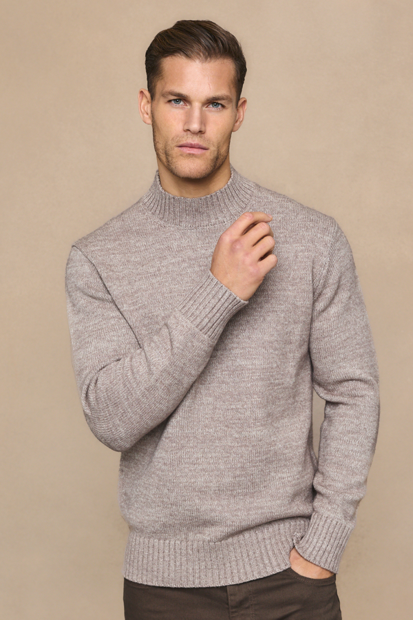 Man wearing a light brown sweater against a beige background